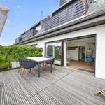 Terrasse mit Tisch, Stühlen und Grillplatz. Durchgang ins Wohnhaus mit Küche.