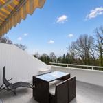 Terrace with table, chairs, and awning. View of trees and sky.