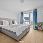 Schlafzimmer mit Doppelbett, TV und Balkonansicht.