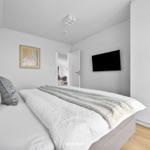 Schlafzimmer mit Bett, TV und Kleiderschrank. Tür führt in Wohnbereich.