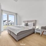 Schlafzimmer mit Bett, Stuhl und Fenster zur Aussicht.