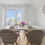 Esstisch mit Stühlen, Fenster und Wanduhr im Esszimmer.