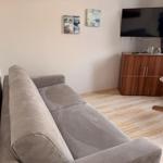 Ein Wohnzimmer mit einem grauen Sofa, einem Holztisch und einem Fernseher auf einem Schrank.