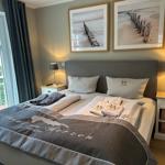 Schlafzimmer mit Doppelbett, zwei Nachttischen und Fenster zum Balkon.
