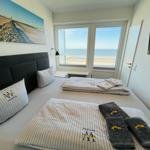 Schlafzimmer mit Blick aufs Meer und TV. Bett mit Handtüchern und Kissen.