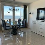 Esszimmer mit Blick aufs Meer, Glas-Tisch, Stühle, TV und Schrank.