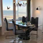 Esszimmer mit Glasplatte und Blick aufs Meer.