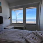 Schlafzimmer mit Blick auf Strand und Meer. Bett mit Bettwäsche und Handtüchern.