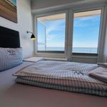 Schlafzimmer mit Blick aufs Meer. Bett mit Bettwäsche und Handtücher.