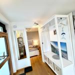 Flur mit Kleiderschrank und Blick in Schlafzimmer mit Bett und Nachttisch.