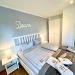 Schlafzimmer mit Doppelbett, Nachttisch und Kleiderschrank. Wanddekoration mit Dream.