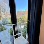 Weißer Stuhl vor Fenster mit Blick auf Garten und Dach