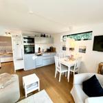 Wohnbereich mit Küche, Esstisch und Schlafzimmer im Hintergrund.