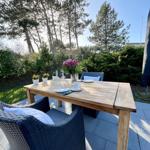 Holztisch mit Stühlen auf Terrasse, Blumen und Tischdekoration