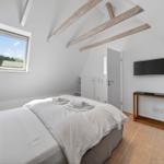 Schlafzimmer mit Dachschrägen, Bett, Fenster und TV.