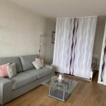 Wohnzimmer mit Sofa, Glas-Tisch und Raumteiler mit Wellenmuster.