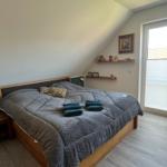 Schlafzimmer mit Dachschräge, Bett, Nachttisch und Fenster mit Jalousien.