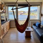 Wohnraum mit Hängematte, Sofa und Blick auf Wasser.