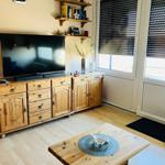 Wohnzimmer mit Holzmöbeln, TV und Fenster mit Jalousien.