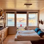 Schlafzimmer mit Blick auf Wasser und Stadt. Holzmöbel, Bett mit Kissen.