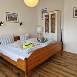 Schlafzimmer mit Holzbett, Schrank und Wandbildern.