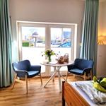 Zimmer mit Bett, Tisch, zwei Stühlen und Fensterblick auf Straße.