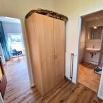 Schlafzimmer mit Kleiderschrank, Bad und Wohnbereich mit Holzboden und blauer Sitzgelegenheit.