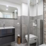 Badezimmer mit Dusche, Toilette und Waschbecken mit Spiegel.