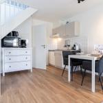 Küche mit Essbereich, Treppe und Holzboden. Weiße Möbel und graue Stühle.