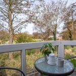 Terrasse mit Tisch, Stühlen und Blick auf Bäume und Häuser.