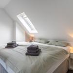 Schlafzimmer mit Dachschrägen, Dachfenster und Bett mit Handtüchern.