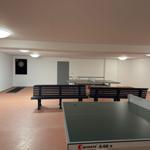 Raum mit zwei Tischtennisplatten und Dartscheibe an der Wand.