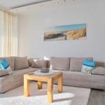 Ein Wohnzimmer mit einem großen Sofa, einem Holztisch und einer Wanddekoration.