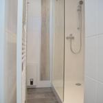Dusche mit Glaswand, weißen Fliesen und Handdusche