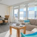 Wohn- und Essbereich mit Sofa, Tisch und Blick auf Balkon.