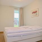 Schlafzimmer mit weißem Bett, Fenster und Bild an der Wand.