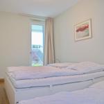 Schlafzimmer mit zwei Betten, Fenster und Wandbild.