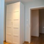 Schlafzimmer mit weißen Schrank und offener Tür zum Flur.