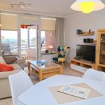 Wohnzimmer mit Sofa, Esstisch und TV. Balkon mit Meerblick.