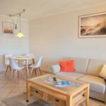 Wohnzimmer mit Sofa, Couchtisch und Essbereich. Wandbild und Beleuchtung sichtbar.