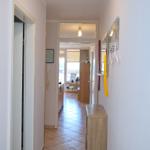 Flur mit Kleiderhaken, Schrank und Blick in Küche und Wohnbereich.