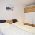 Schlafzimmer mit Doppelbett, Holzschrank und Wandbild.