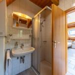Bathroom with shower, sink, and mirror. Door leads to bedroom.