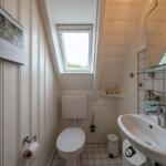 Bathroom with toilet, sink, and skylight. Calendar on the wall.