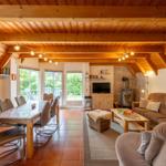 Living and dining area with wooden ceiling, sofa, dining table, and fireplace.