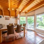 Dining room with wooden ceiling, table and chairs, view of garden.