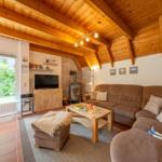 Living room with wooden ceiling, sofa, fireplace, and TV.
