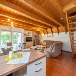 Living and dining area with wooden ceiling, sofa, armchair, and kitchen island.