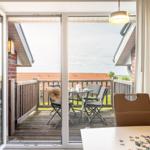 Terrasse mit Tisch und Stühlen. Durch Glastüren ist sie vom Innenraum zugänglich.