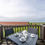 Terrasse mit Tisch und Stühlen, Blick auf Grünflächen und Gebäude